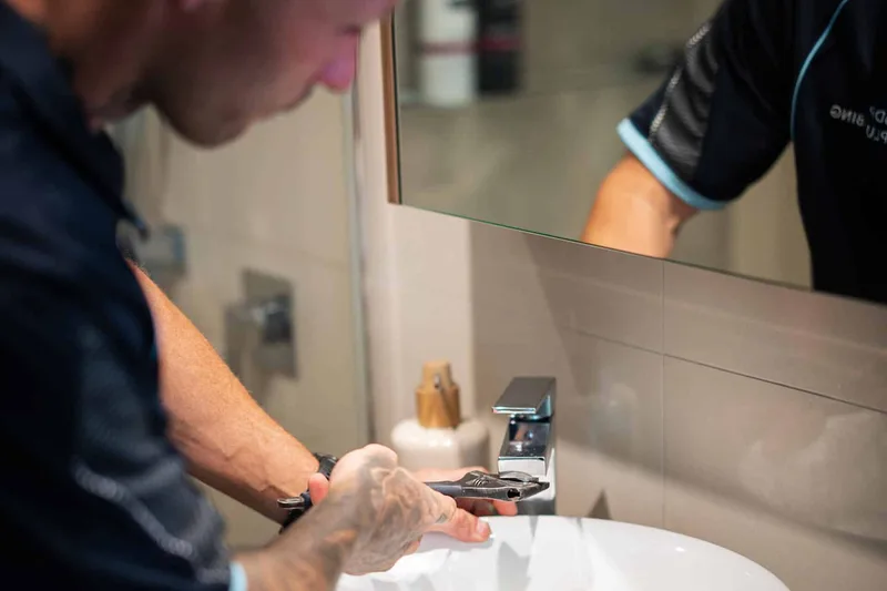 Plumber tightening a basin tap with a wrench