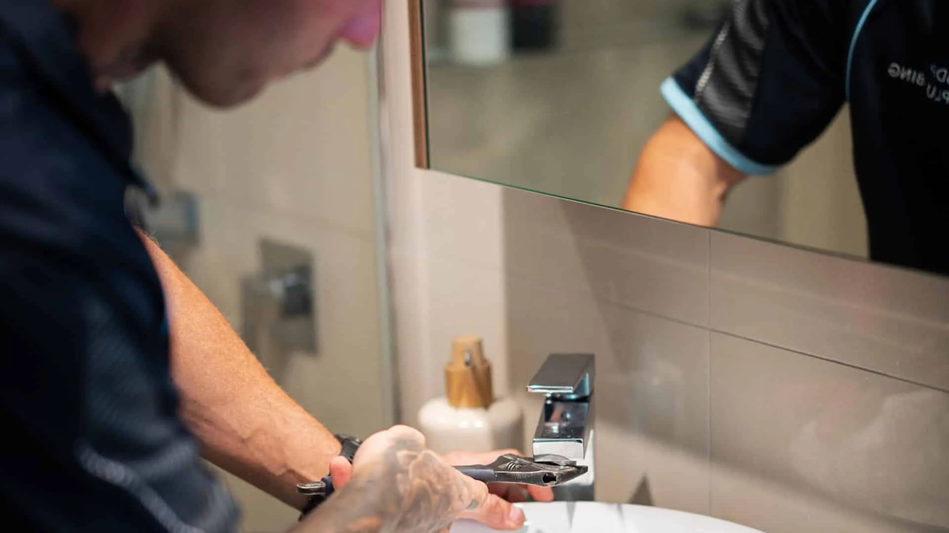 Plumber tightening a basin tap with a wrench