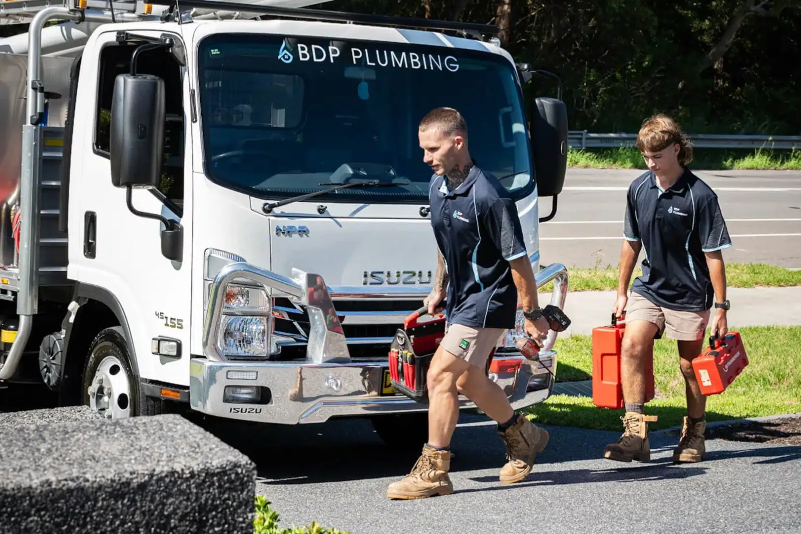 Two plumbers walking from the truck with tool cases