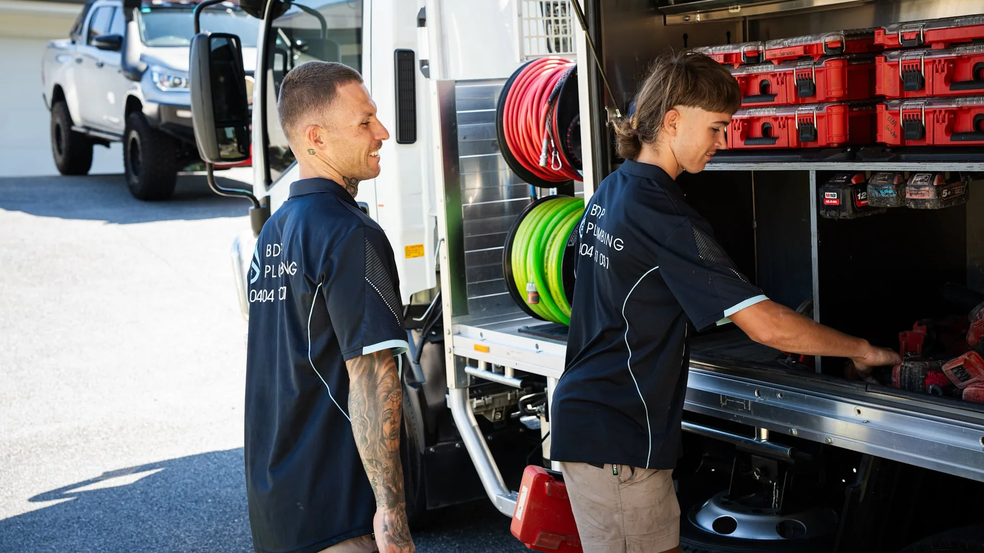 Two plumbers loading gear from the truck lockers