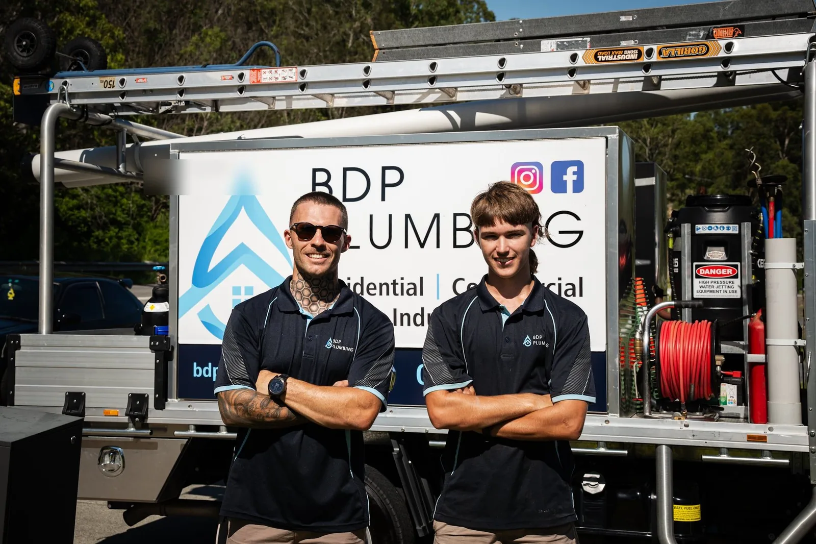 Two plumbers standing in front of the service truck