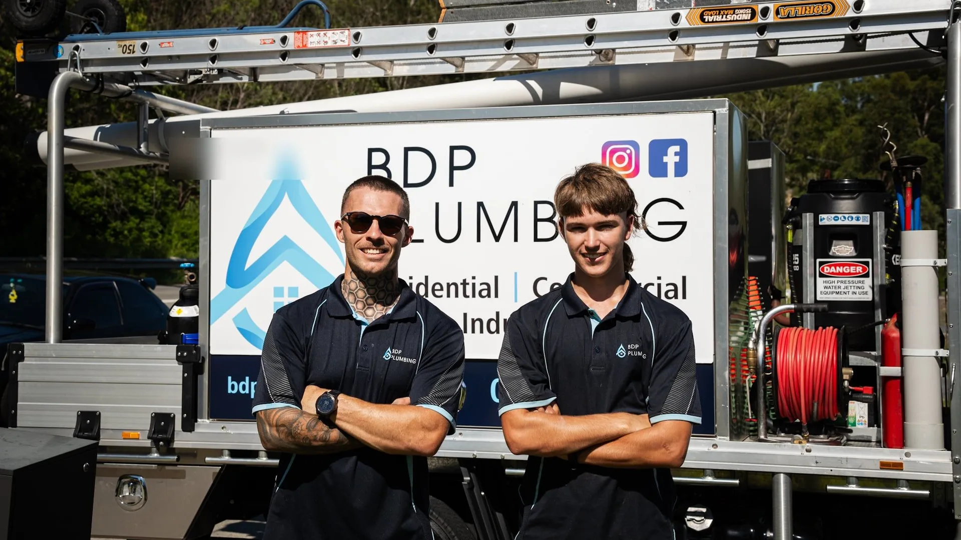 Two plumbers standing in front of the service truck