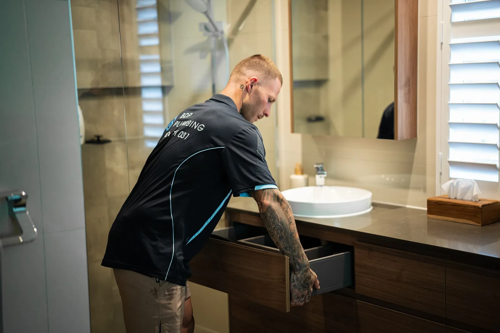 Plumber checking the plumbing behind a bathroom vanity